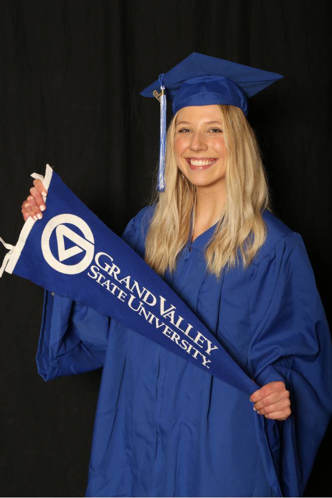 GradFest attendee holding up the gvsu flag by herself